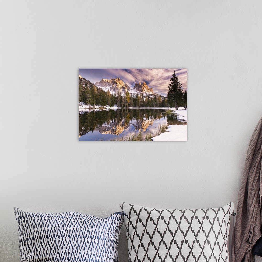 A bohemian room featuring A photograph of a mountain range and forest reflected in still water, under purple clouds.