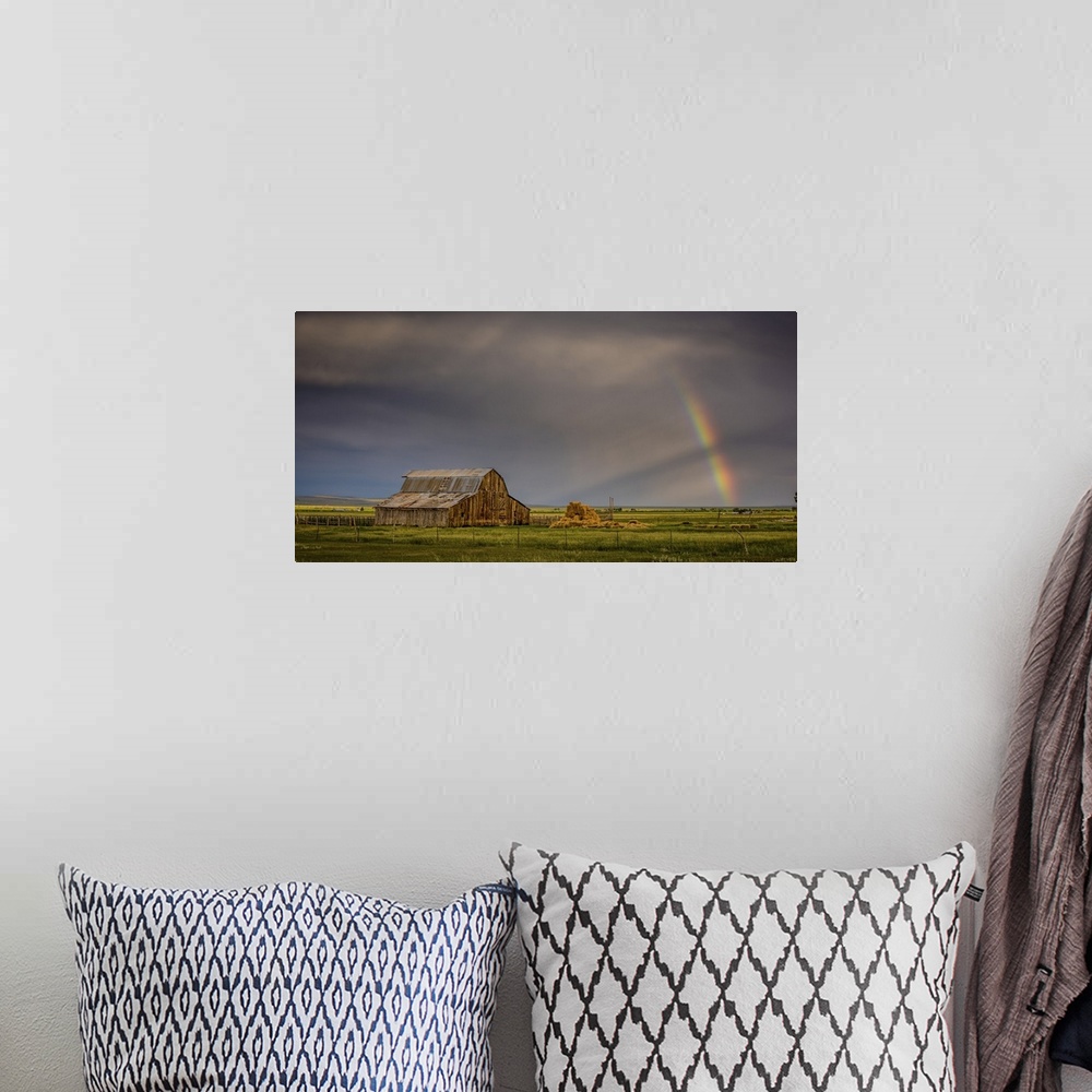 A bohemian room featuring A photograph of an old barn in a wilderness landscape with a rainbow peaking out from clouds in t...