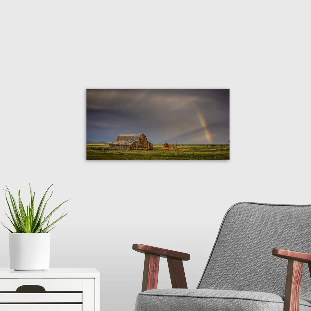 A modern room featuring A photograph of an old barn in a wilderness landscape with a rainbow peaking out from clouds in t...