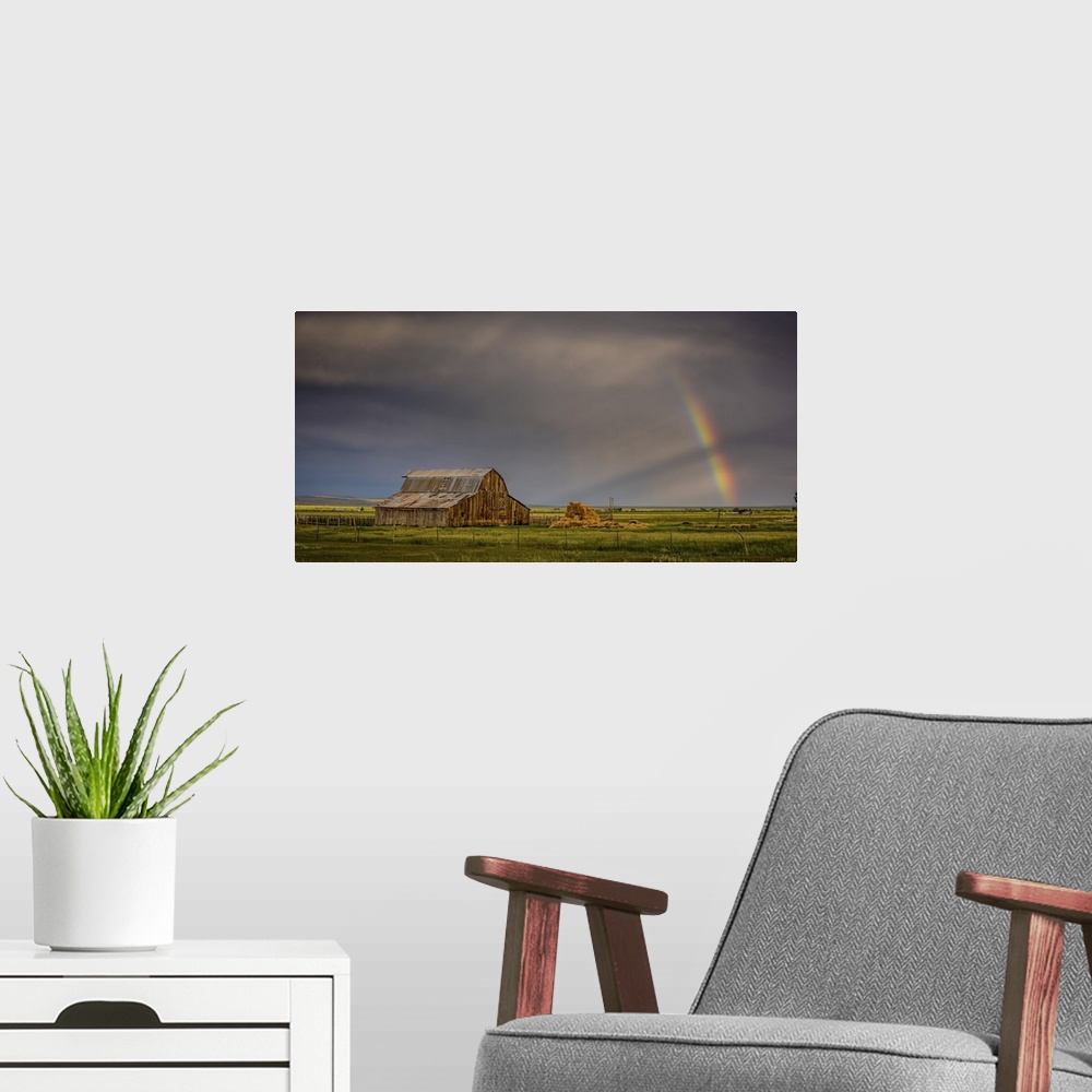 A modern room featuring A photograph of an old barn in a wilderness landscape with a rainbow peaking out from clouds in t...