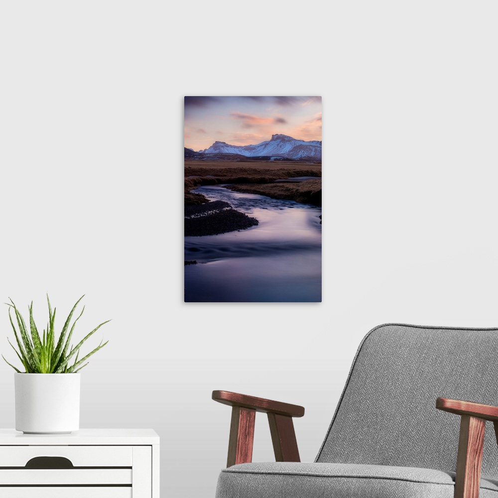A modern room featuring Landscape photograph of a winding river in a frozen valley with snow covered mountains in the dis...