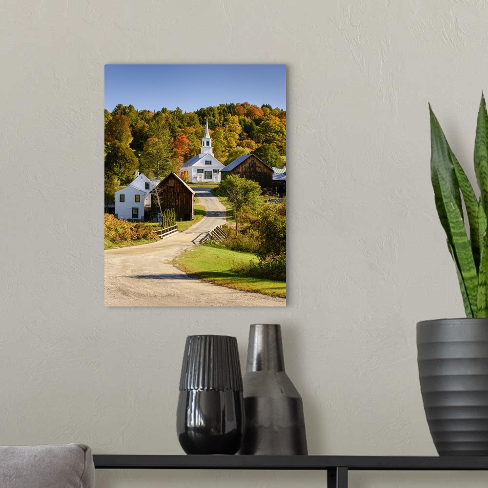 A modern room featuring Photograph of a gravel road leading up the hill to a white church surrounded by various wooden bu...