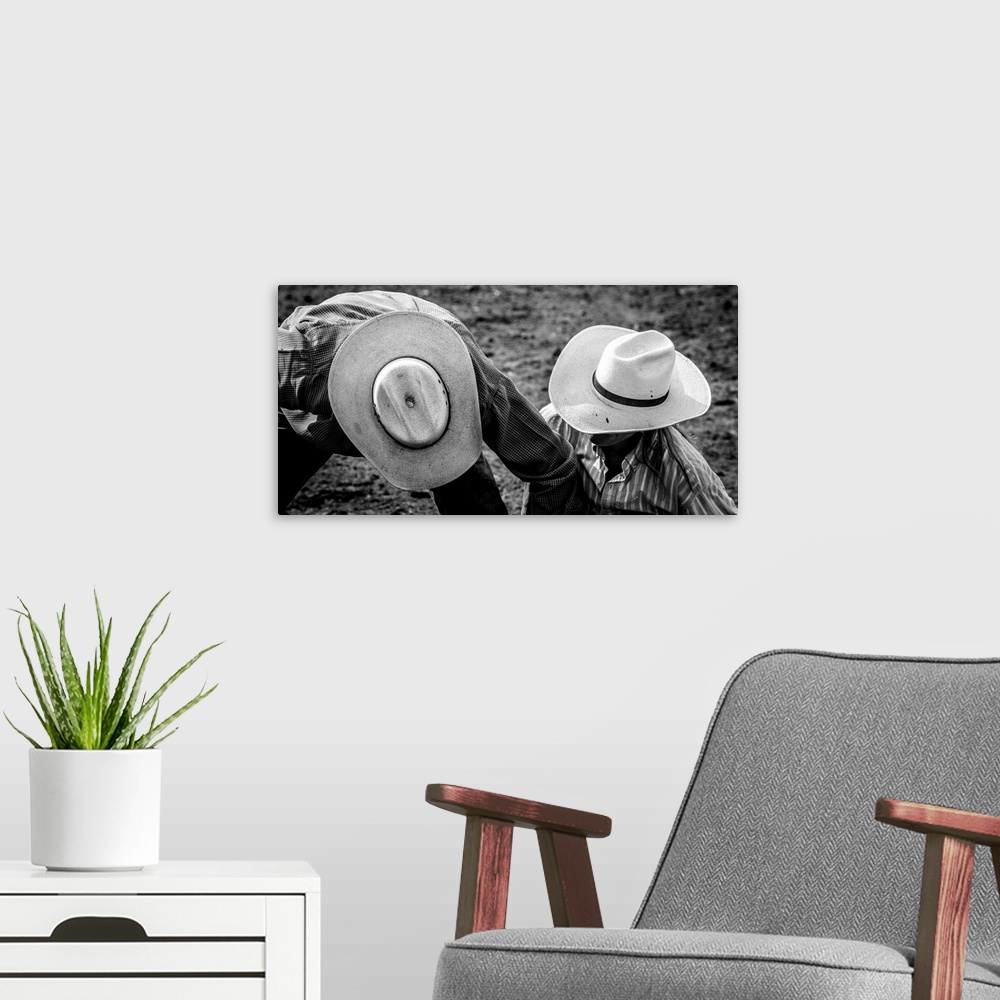 A modern room featuring Black and white photograph of two people wearing cowboy hats on the ground at a rodeo.