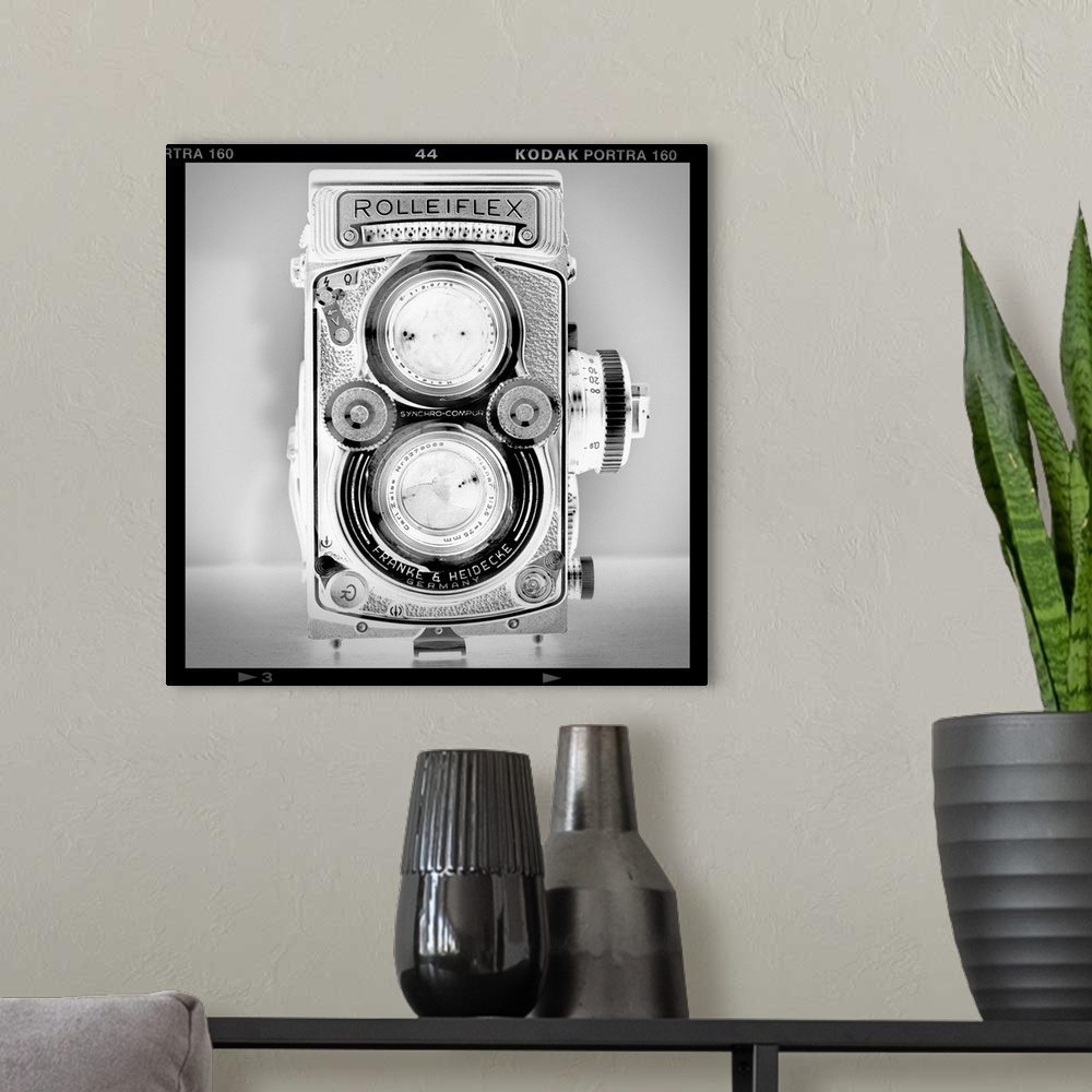 A modern room featuring A black and white fine art photograph of an antique rolliflex camera within a film cell border