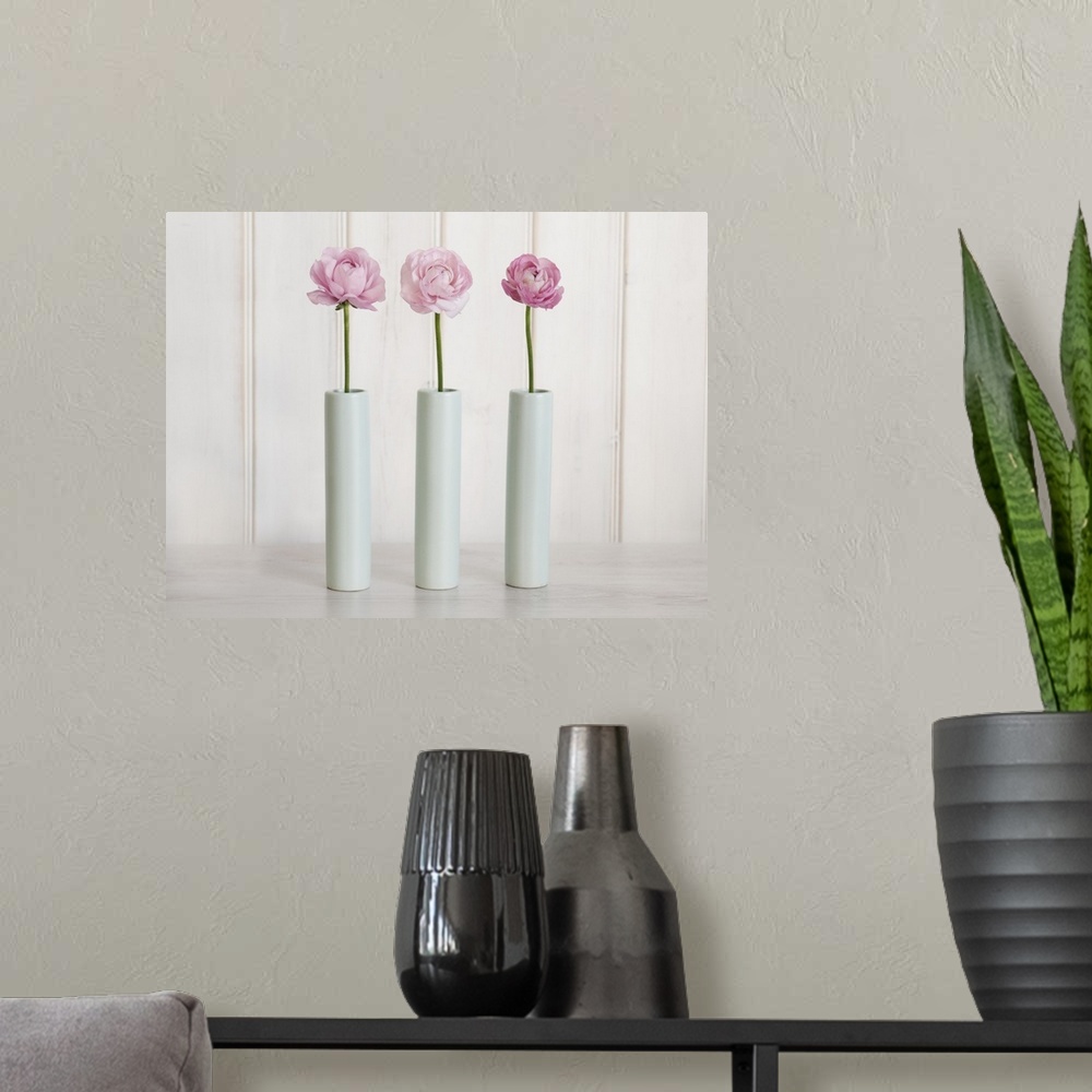 A modern room featuring Row Of 3 Pink Flowers In Blue Vases