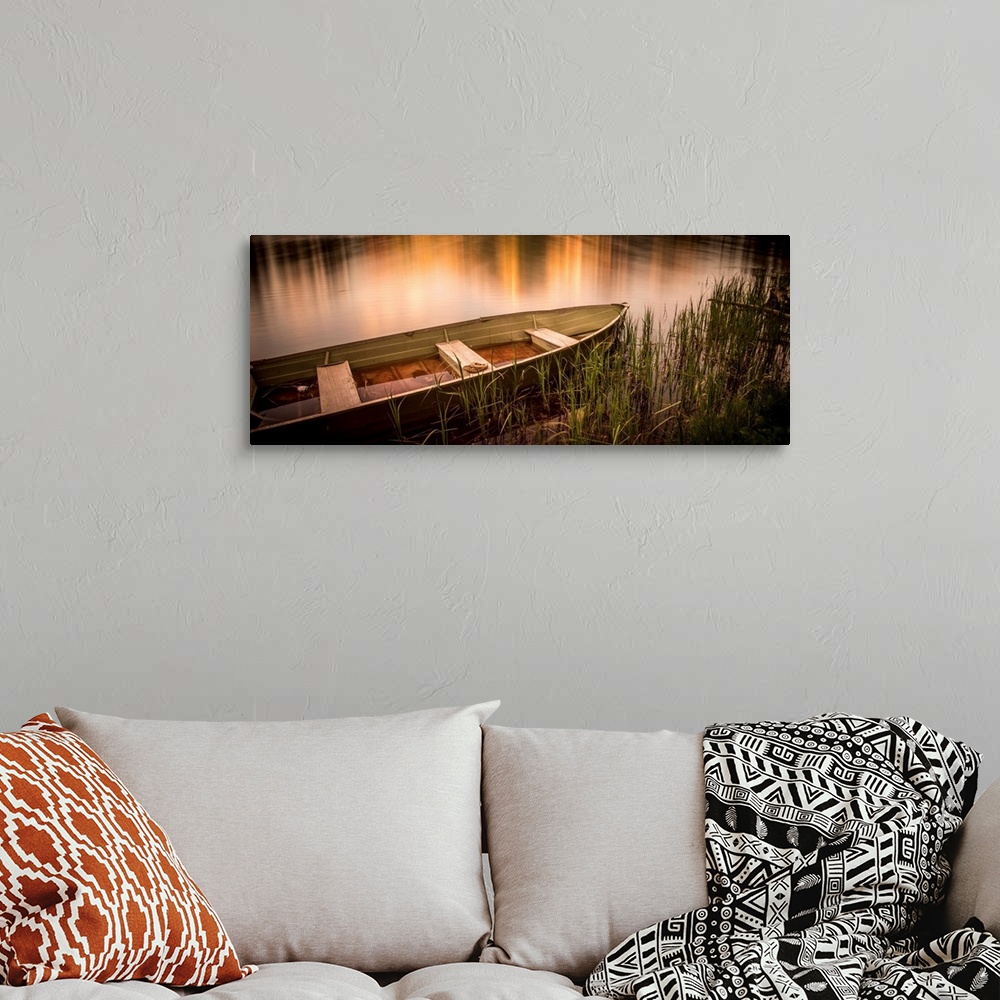 A bohemian room featuring A photograph of a rowboat siting still in the water.