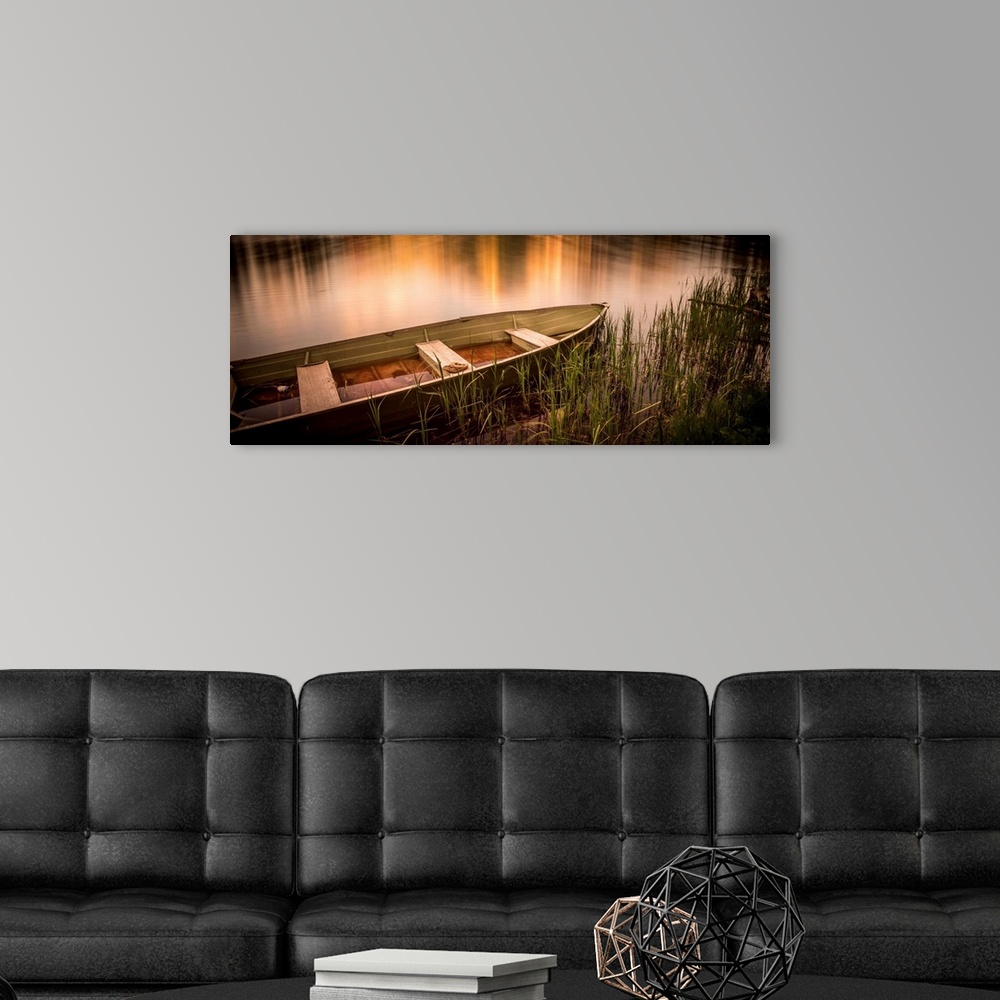 A modern room featuring A photograph of a rowboat siting still in the water.