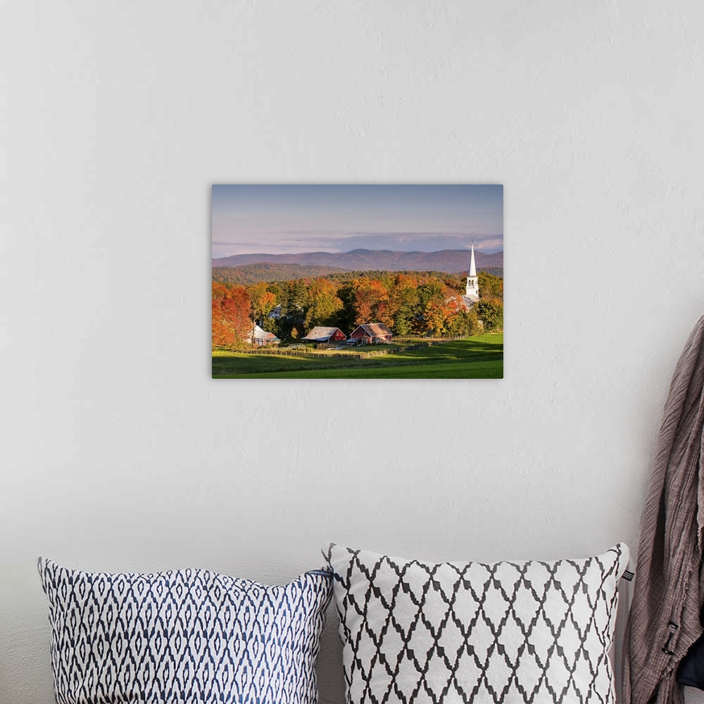 A bohemian room featuring A photograph of the steeple of a white church sticking high up out of the autumn colored forest.