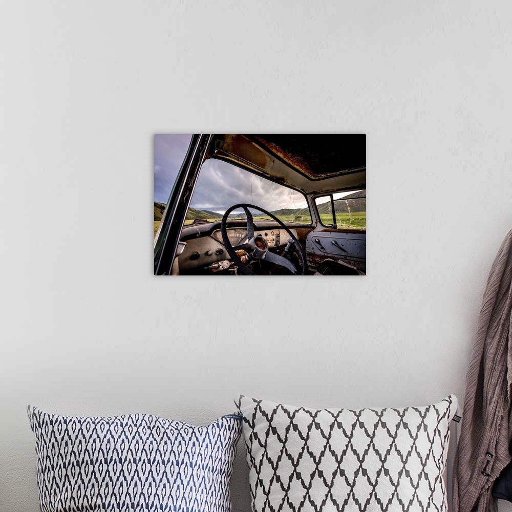 A bohemian room featuring Photograph of the inside of an old abandoned car full of rust in the middle of a valley.