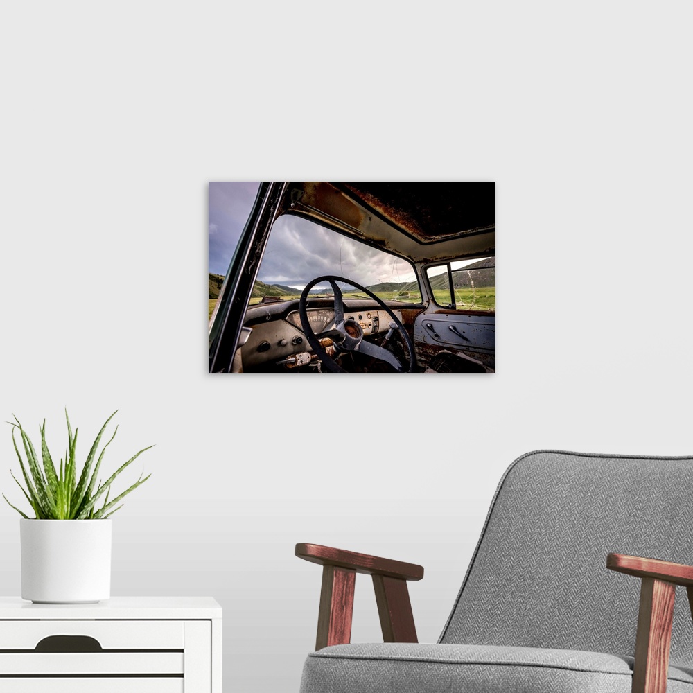 A modern room featuring Photograph of the inside of an old abandoned car full of rust in the middle of a valley.