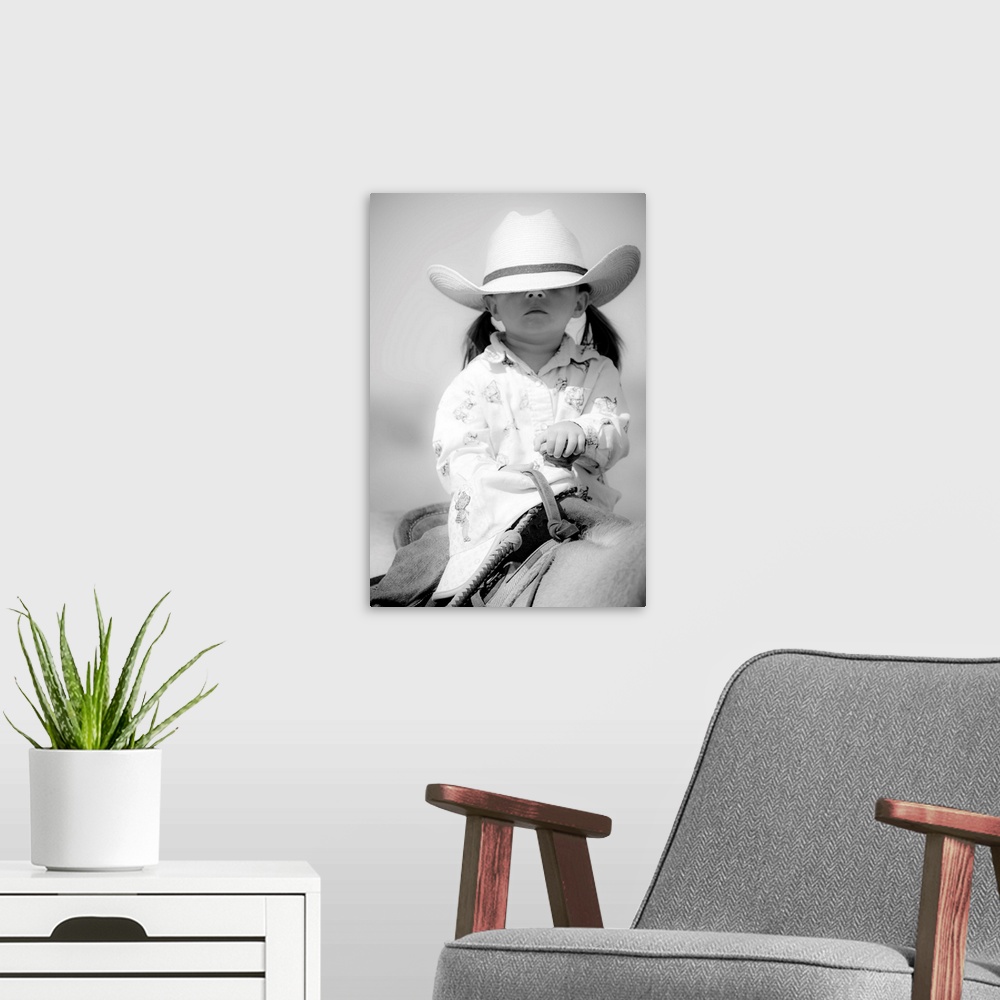 A modern room featuring Black and white portrait of a young girl with a cowboy hat covering her eyes on horseback.