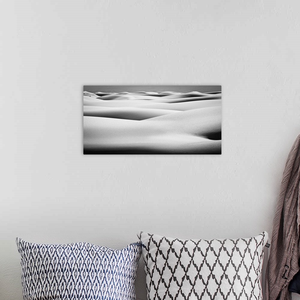 A bohemian room featuring Black and white landscape photograph of contrasting hilly sand dunes.