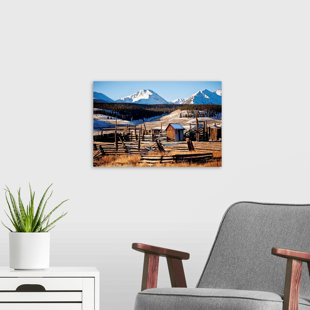 A modern room featuring Landscape photograph of run down wooden structures in the valley surrounded by snow covered mount...