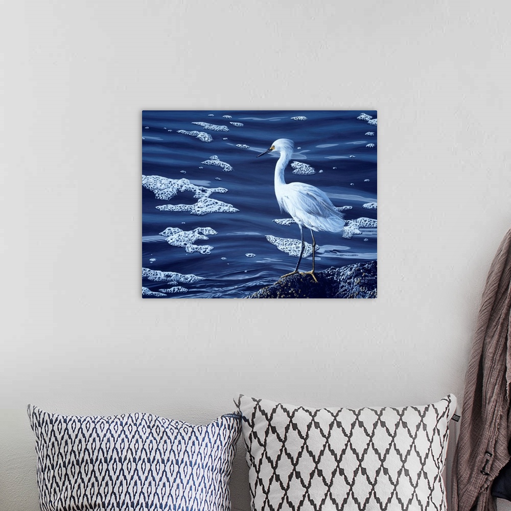 A bohemian room featuring A snowy egret rests on a rock near the water's edge.