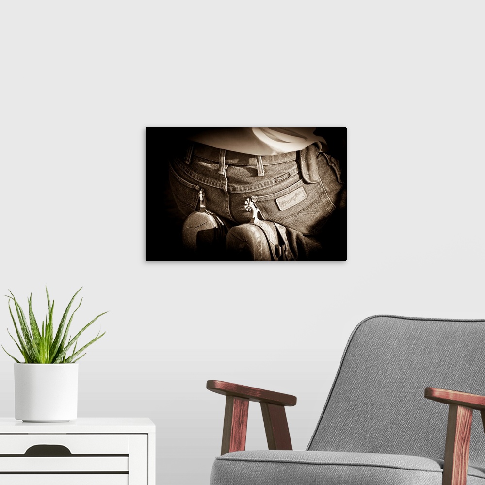 A modern room featuring Sepia photograph of a cowboy on his knees with spurs resting on his jeans with a black vignette a...