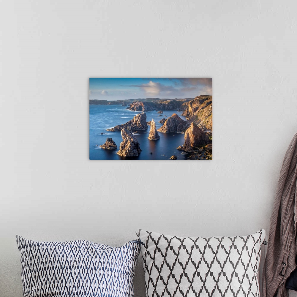 A bohemian room featuring Landscape photograph of a rocky cliff lined ocean with rock stacks in the water.