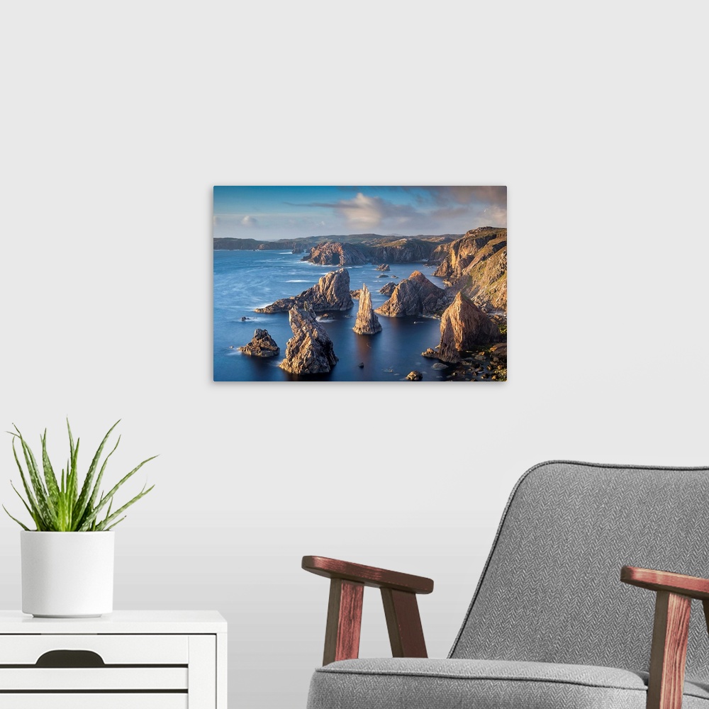 A modern room featuring Landscape photograph of a rocky cliff lined ocean with rock stacks in the water.