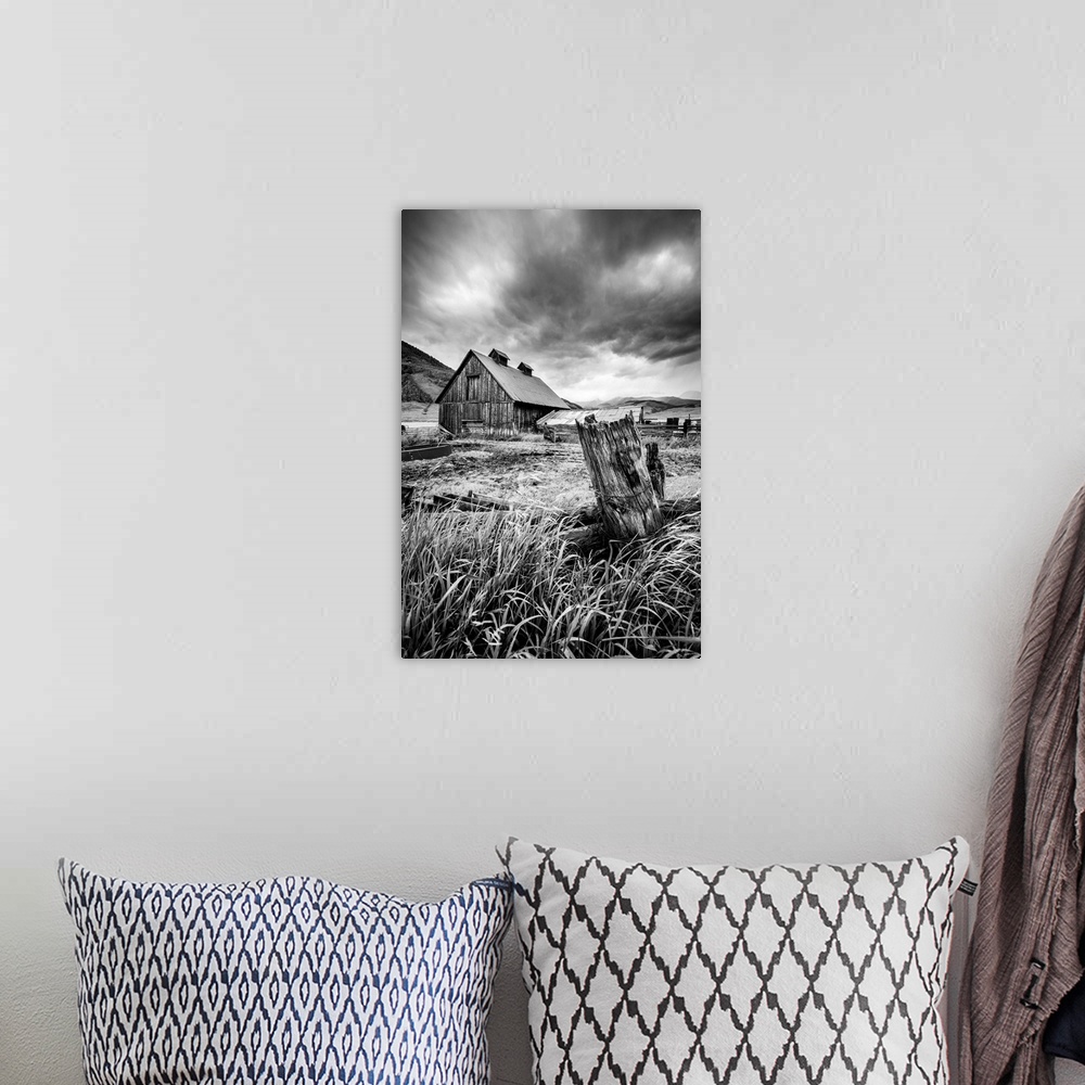 A bohemian room featuring A black and white photograph of a barn and field under a storm clouds.