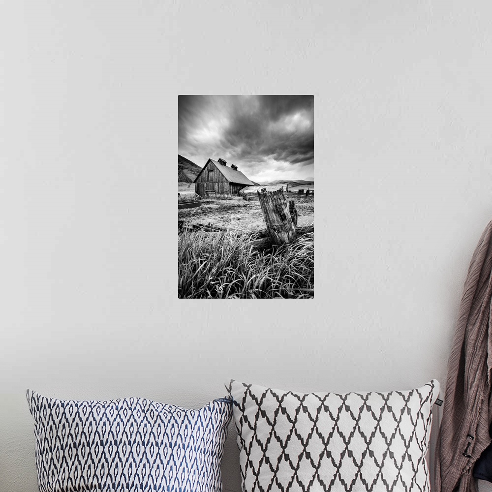 A bohemian room featuring A black and white photograph of a barn and field under a storm clouds.