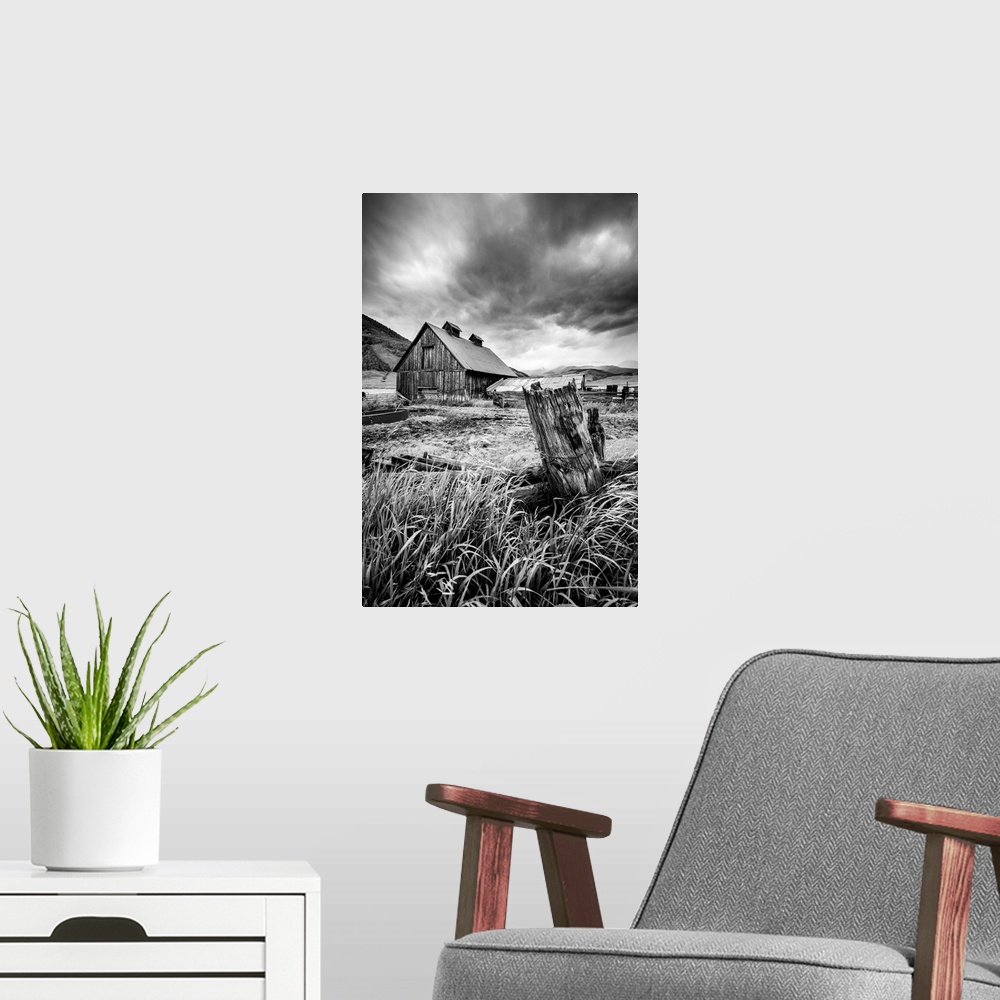 A modern room featuring A black and white photograph of a barn and field under a storm clouds.