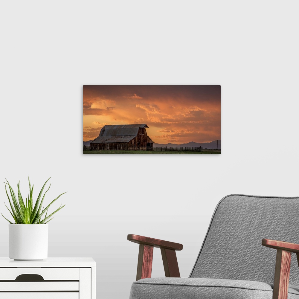 A modern room featuring A photograph of an old barn under illuminated clouds of a sunset.
