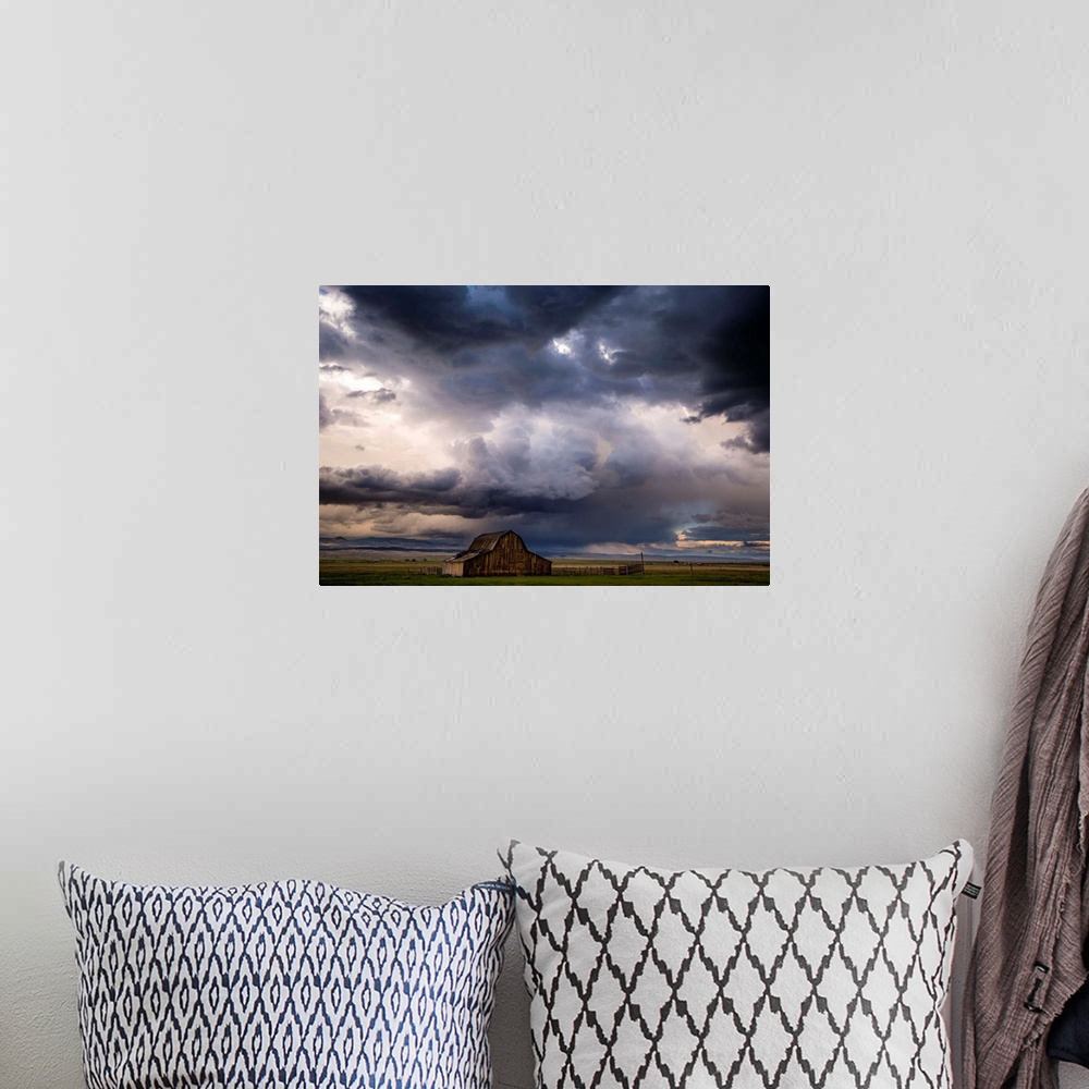 A bohemian room featuring A photograph of a farm landscape under the dark clouds of an incoming storm.