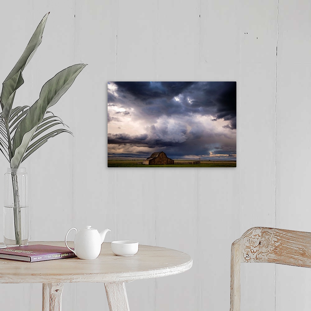 A farmhouse room featuring A photograph of a farm landscape under the dark clouds of an incoming storm.