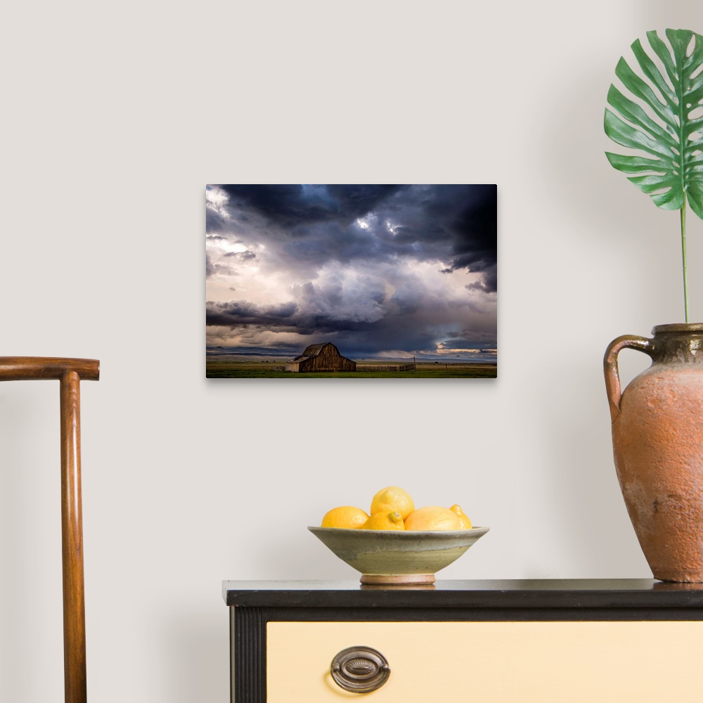 A traditional room featuring A photograph of a farm landscape under the dark clouds of an incoming storm.