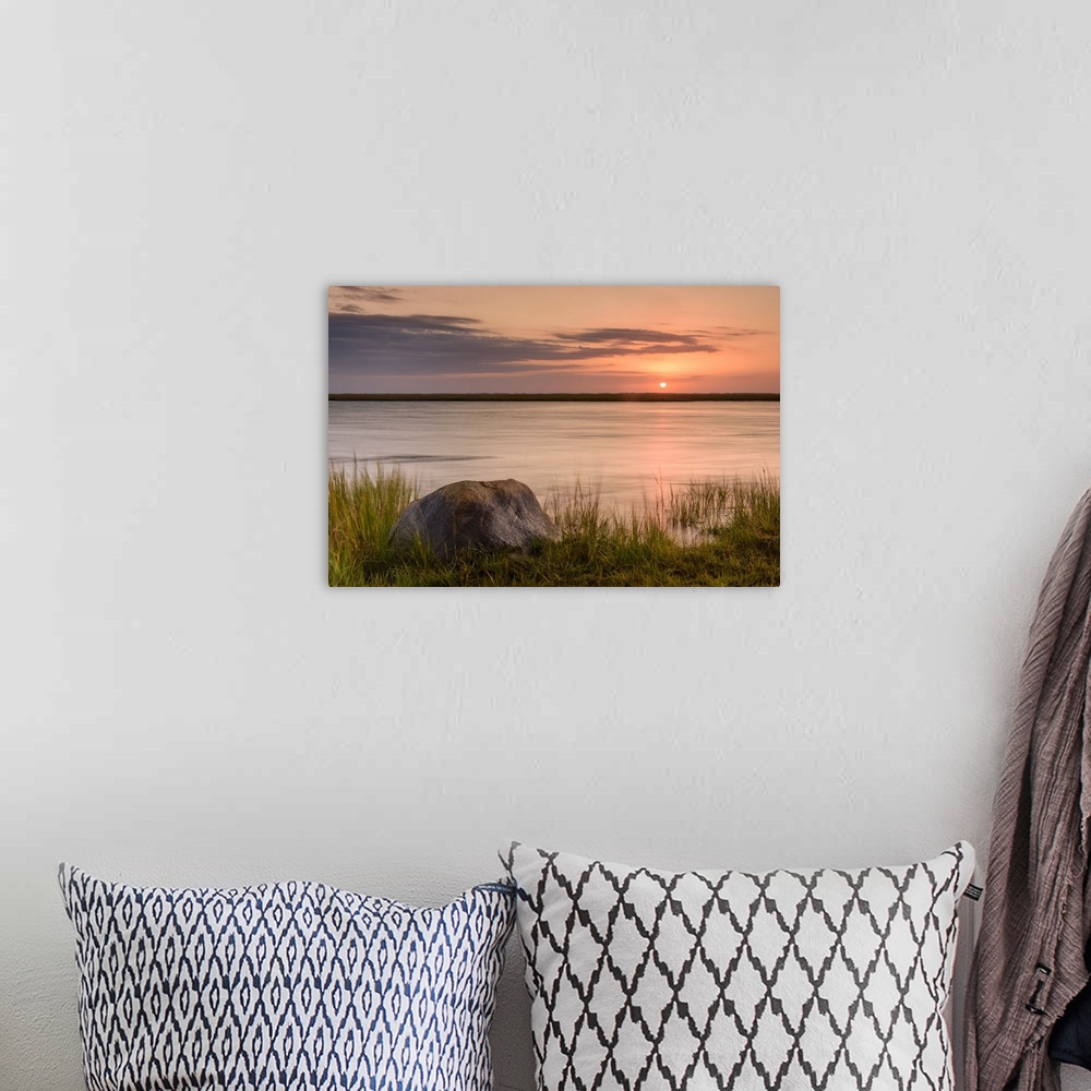 A bohemian room featuring Landscape photograph of a warm sunset over water with a rock in the foreground.