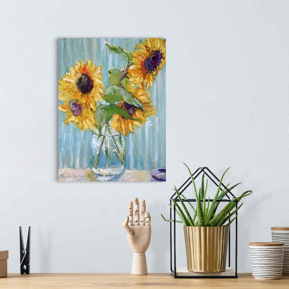A bohemian room featuring Sunflowers in a clear glass vase.