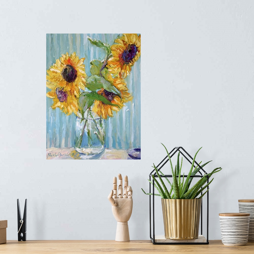 A bohemian room featuring Sunflowers in a clear glass vase.