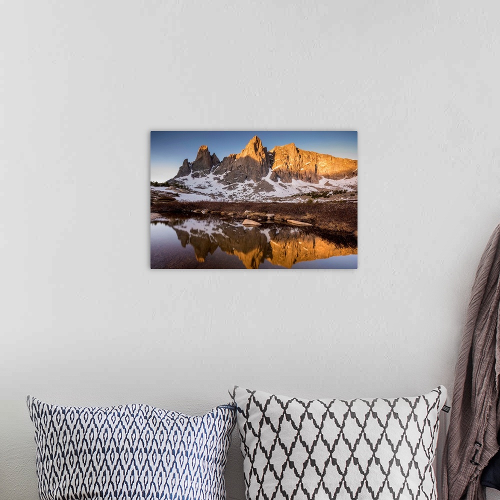 A bohemian room featuring Landscape photograph of a rocky mountain range covered in snow reflecting onto still water.