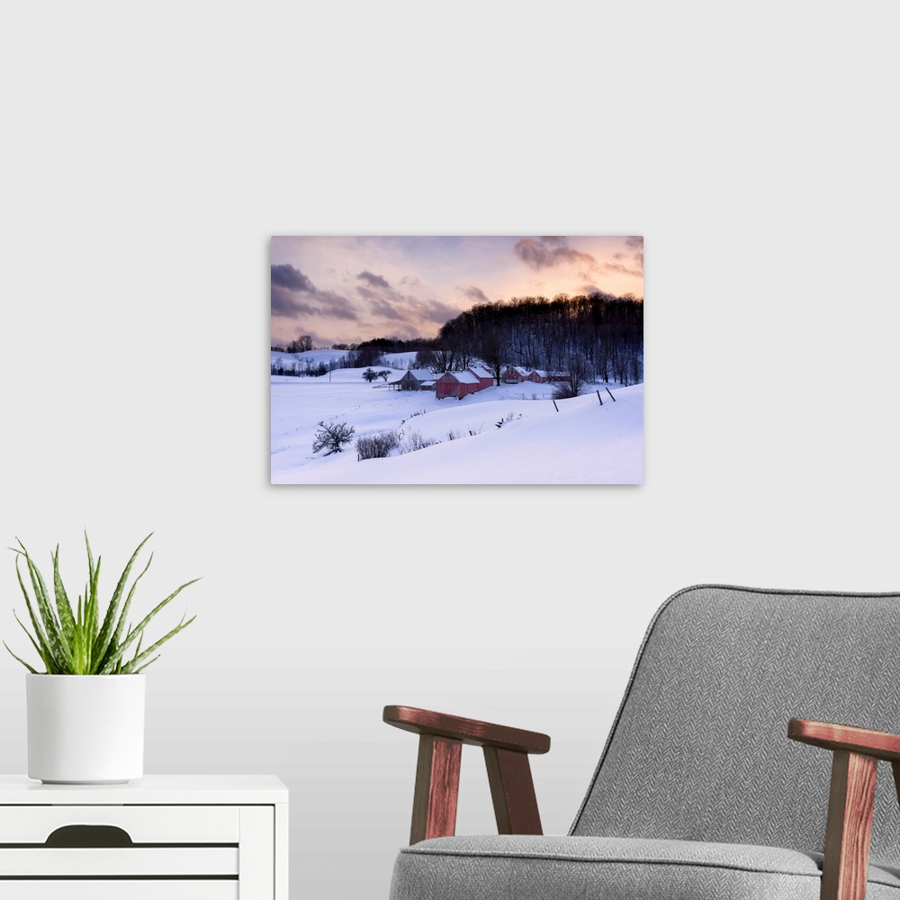 A modern room featuring Landscape photograph of a snowy Winter farm with red wooden buildings and a pretty sunset.