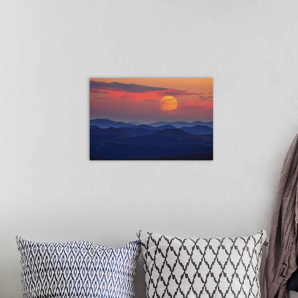 A bohemian room featuring A glowing moon at dawn over misty mountains.