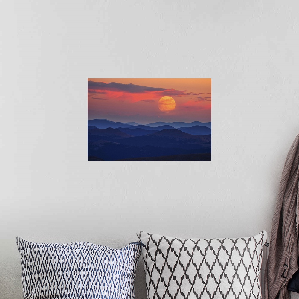 A bohemian room featuring A glowing moon at dawn over misty mountains.