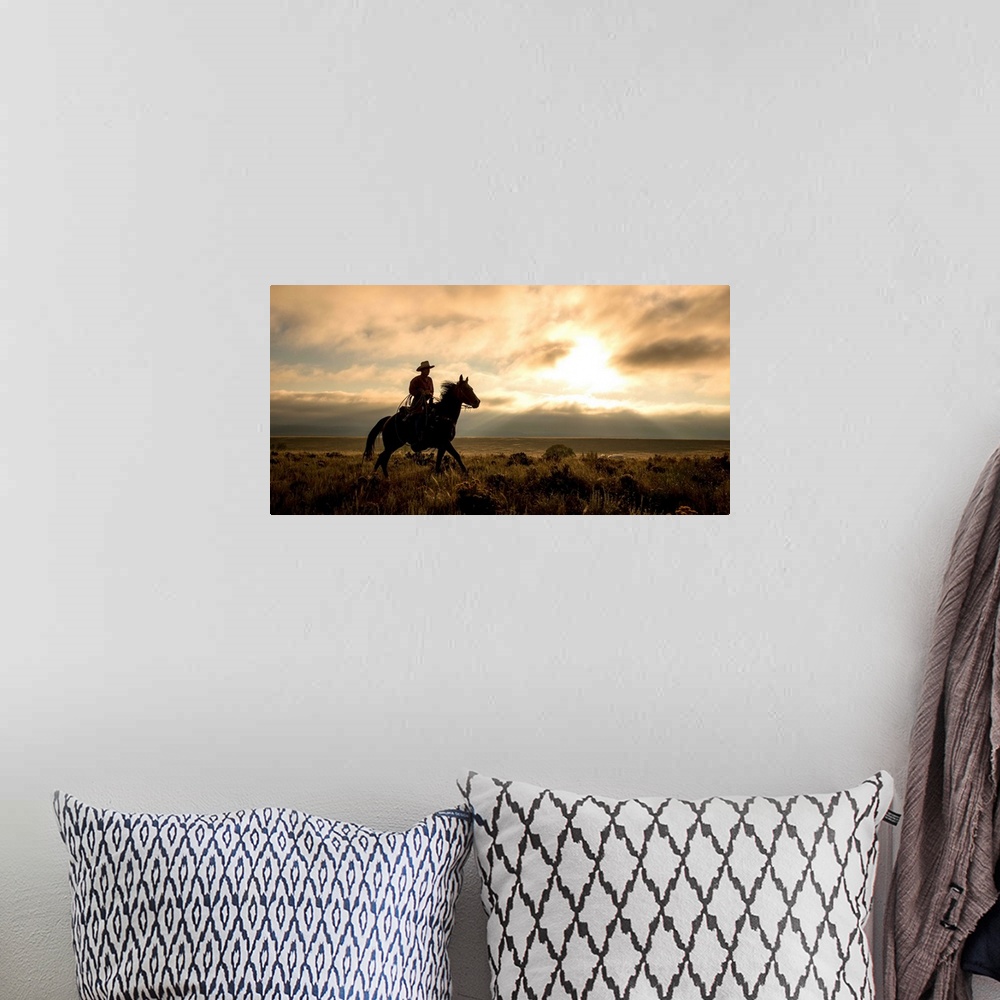 A bohemian room featuring Photograph of a cowboy riding a horse through a field at sunset.