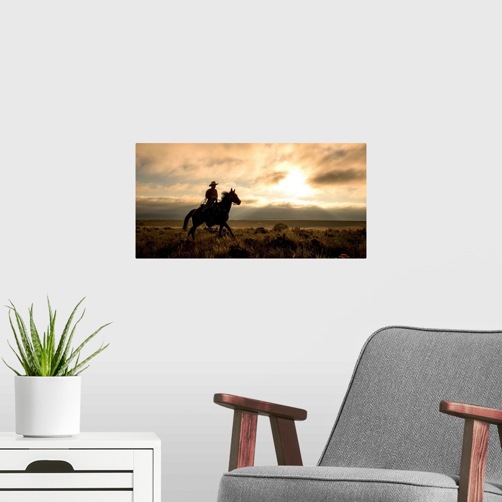 A modern room featuring Photograph of a cowboy riding a horse through a field at sunset.