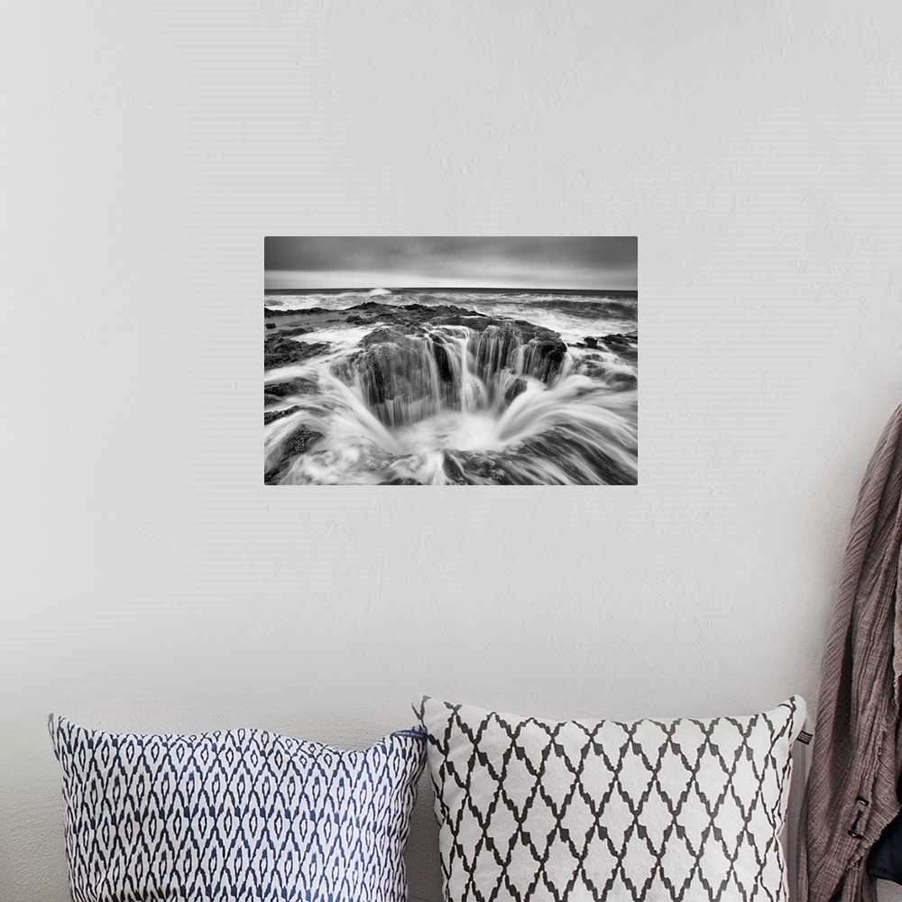 A bohemian room featuring A black and white photograph of a well in the ocean surrounded by rushing water.