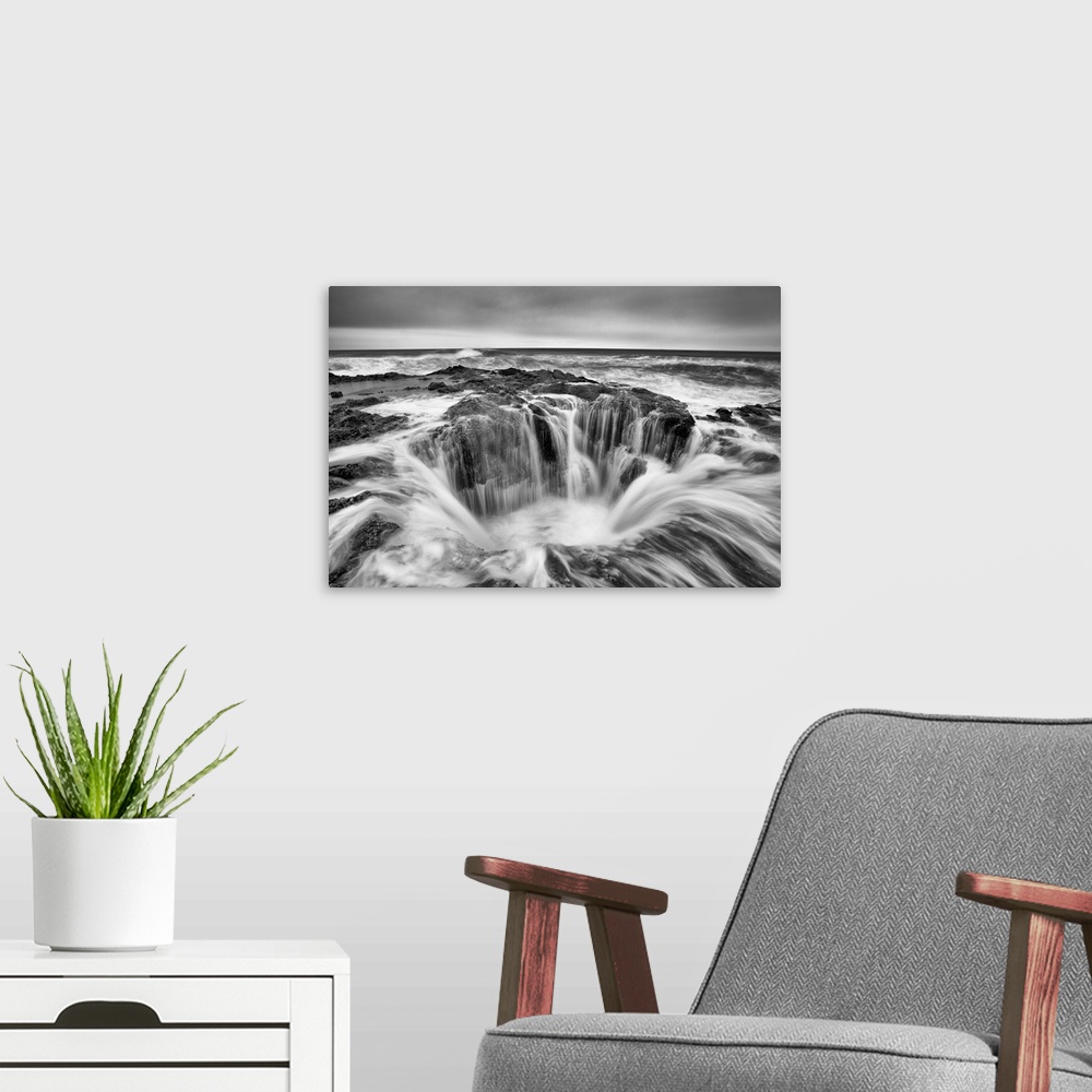 A modern room featuring A black and white photograph of a well in the ocean surrounded by rushing water.