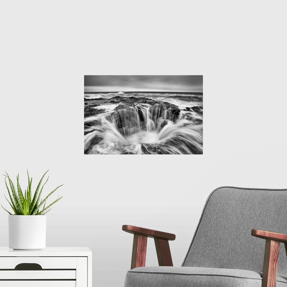 A modern room featuring A black and white photograph of a well in the ocean surrounded by rushing water.