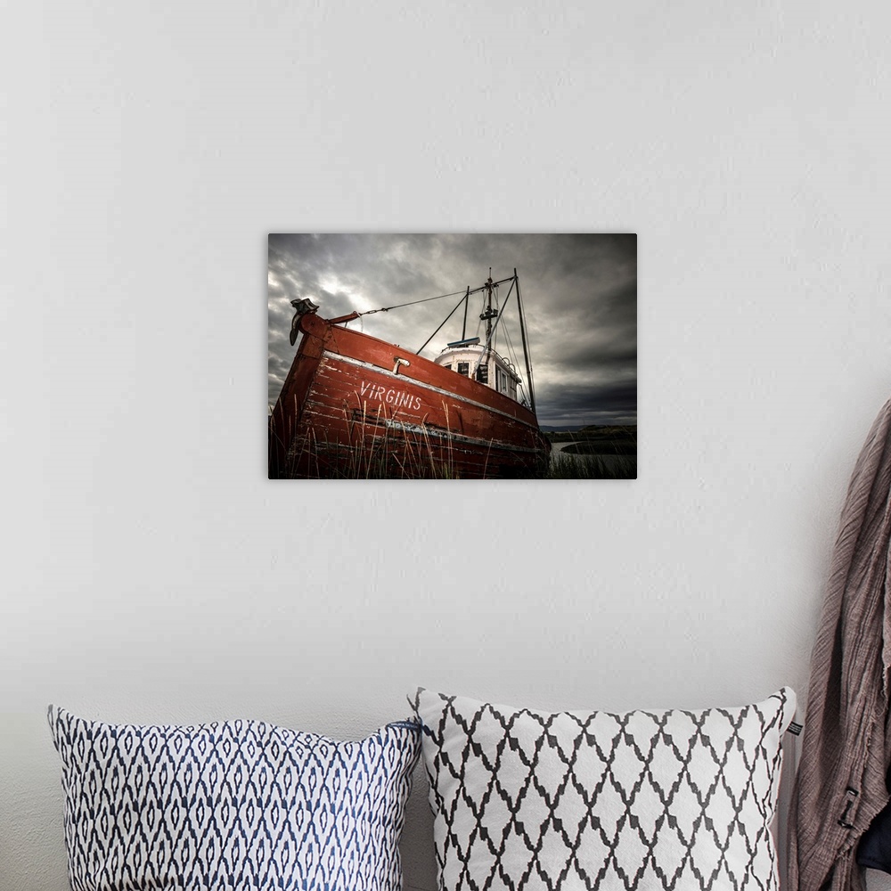 A bohemian room featuring Photograph of an old red boat called "Virginis" pulled up on the shore on a dark overcast day.