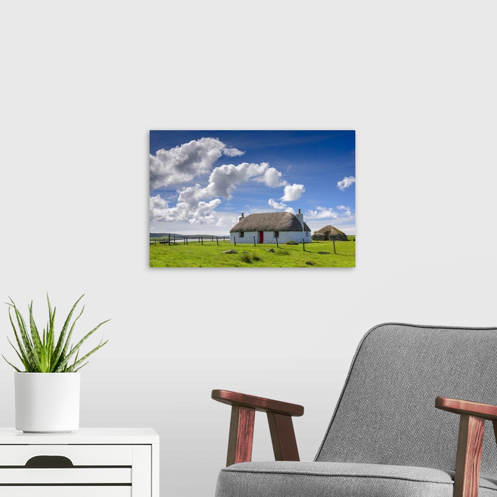 A modern room featuring Beautiful photograph of a white house with a red door in the countryside with white fluffy clouds...