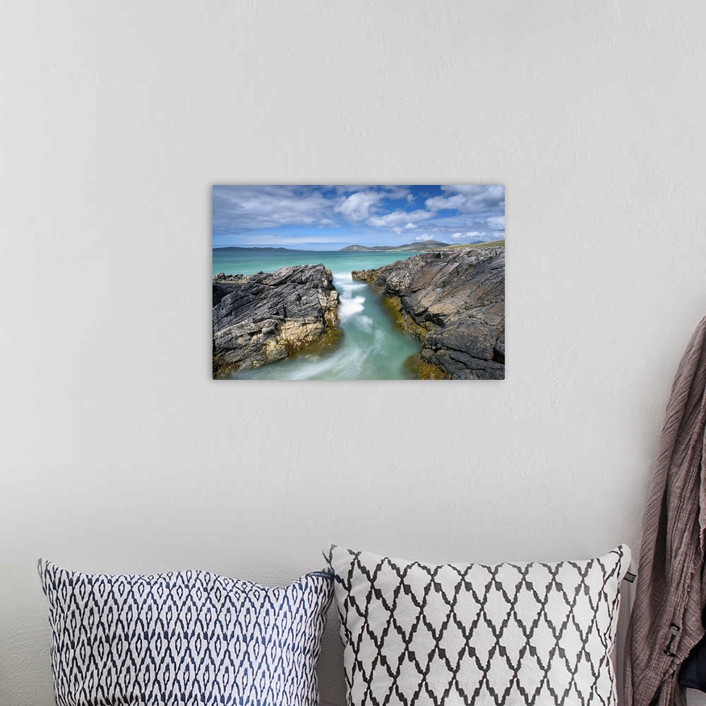A bohemian room featuring Landscape photograph of crystal blue waters rushing though a gap between rocky cliffs.