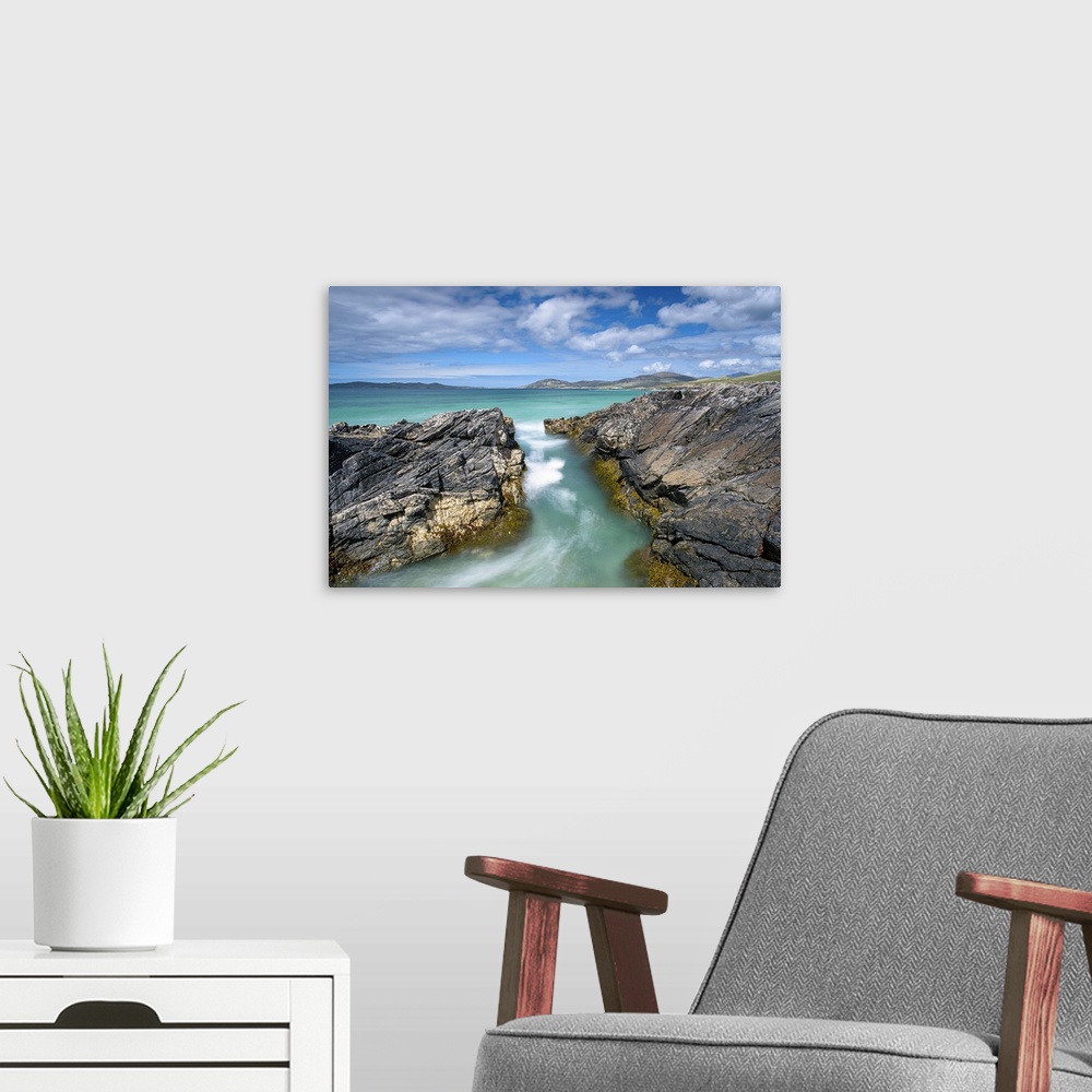 A modern room featuring Landscape photograph of crystal blue waters rushing though a gap between rocky cliffs.