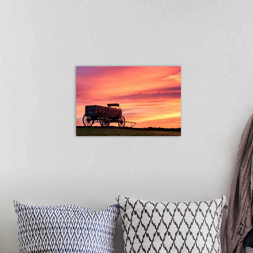A bohemian room featuring Landscape photograph of a horse drawn, wooden wagon in a field with a stunning warm sunset.