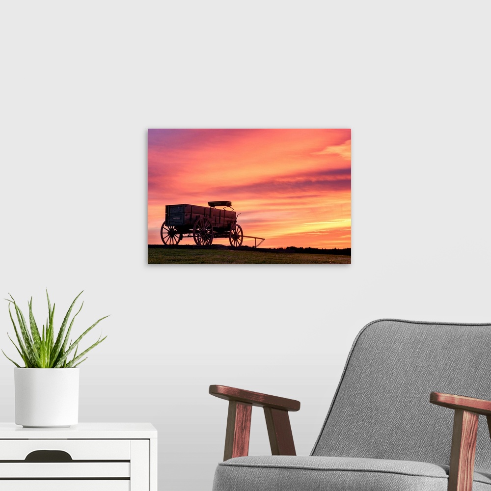 A modern room featuring Landscape photograph of a horse drawn, wooden wagon in a field with a stunning warm sunset.