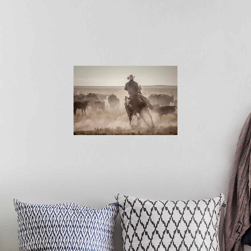 A bohemian room featuring Action photograph of a cowboy on horseback herding cattle.