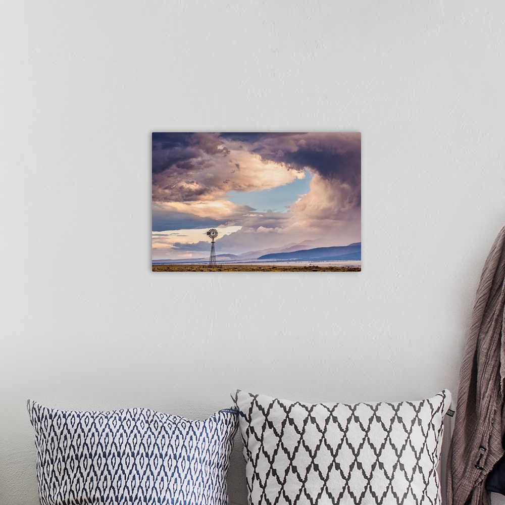 A bohemian room featuring Landscape photograph of a windmill in a field with a mountain range in the background and a drama...