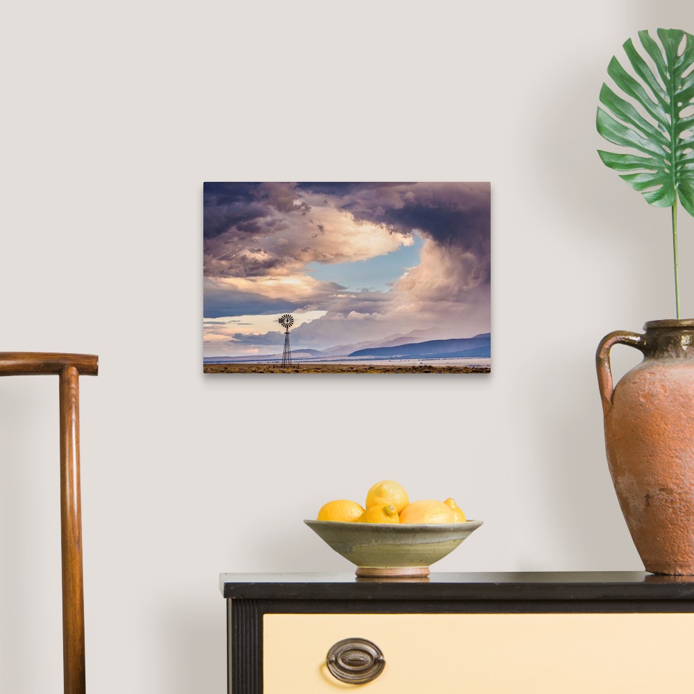 A traditional room featuring Landscape photograph of a windmill in a field with a mountain range in the background and a drama...