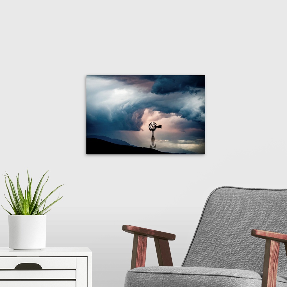 A modern room featuring Landscape photograph with a silhouetted windmill amongst rolling hills and a dramatic cloudy sky.
